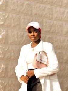 Denim jorts styled with a white blazer, pink flats, pink scarf, matching bag and cap.