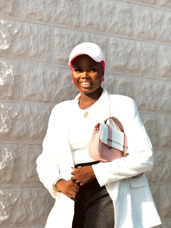 Denim jorts styled with a white blazer, pink flats, pink scarf, matching bag and cap.