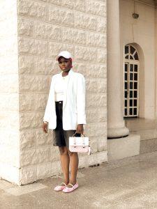Denim jorts styled with a white blazer, pink flats, pink scarf, matching bag and cap.