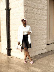 Denim jorts styled with a white blazer, pink flats, pink scarf, matching bag and cap.